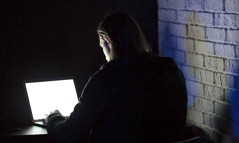 Illustrasjon av innsidetrussel med mann i mørkt rom foran en PC